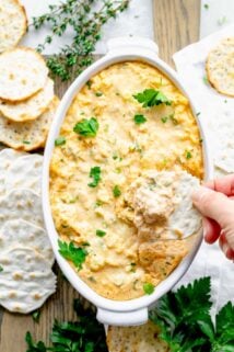 overhead view of the dip with a hand dipping a cracker into it