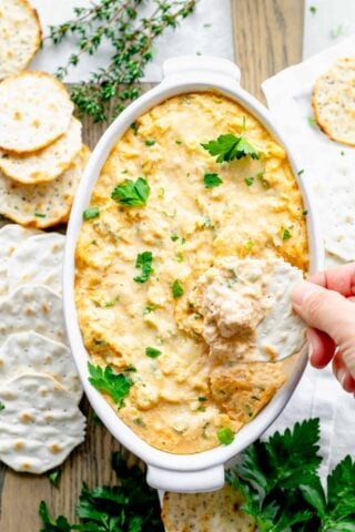 overhead view of the dip with a hand dipping a cracker into it