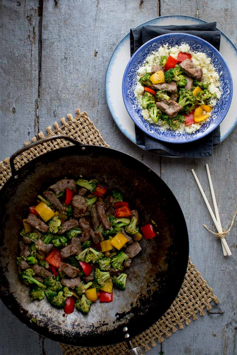 Clean eating beef recipes in a serving bowl and in a wok
