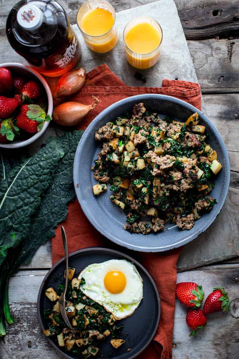 Kale Breakfast Hash in a bowl alongside strawberries and orange juice
