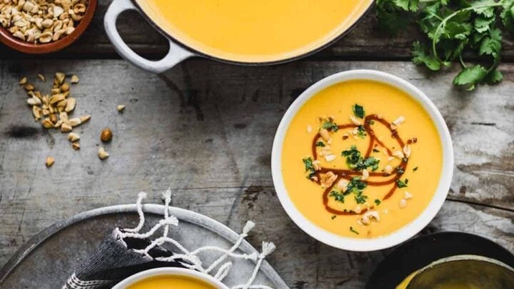 a pot with soup and two bowls from overhead with garnishes on a rustic gray tabletop