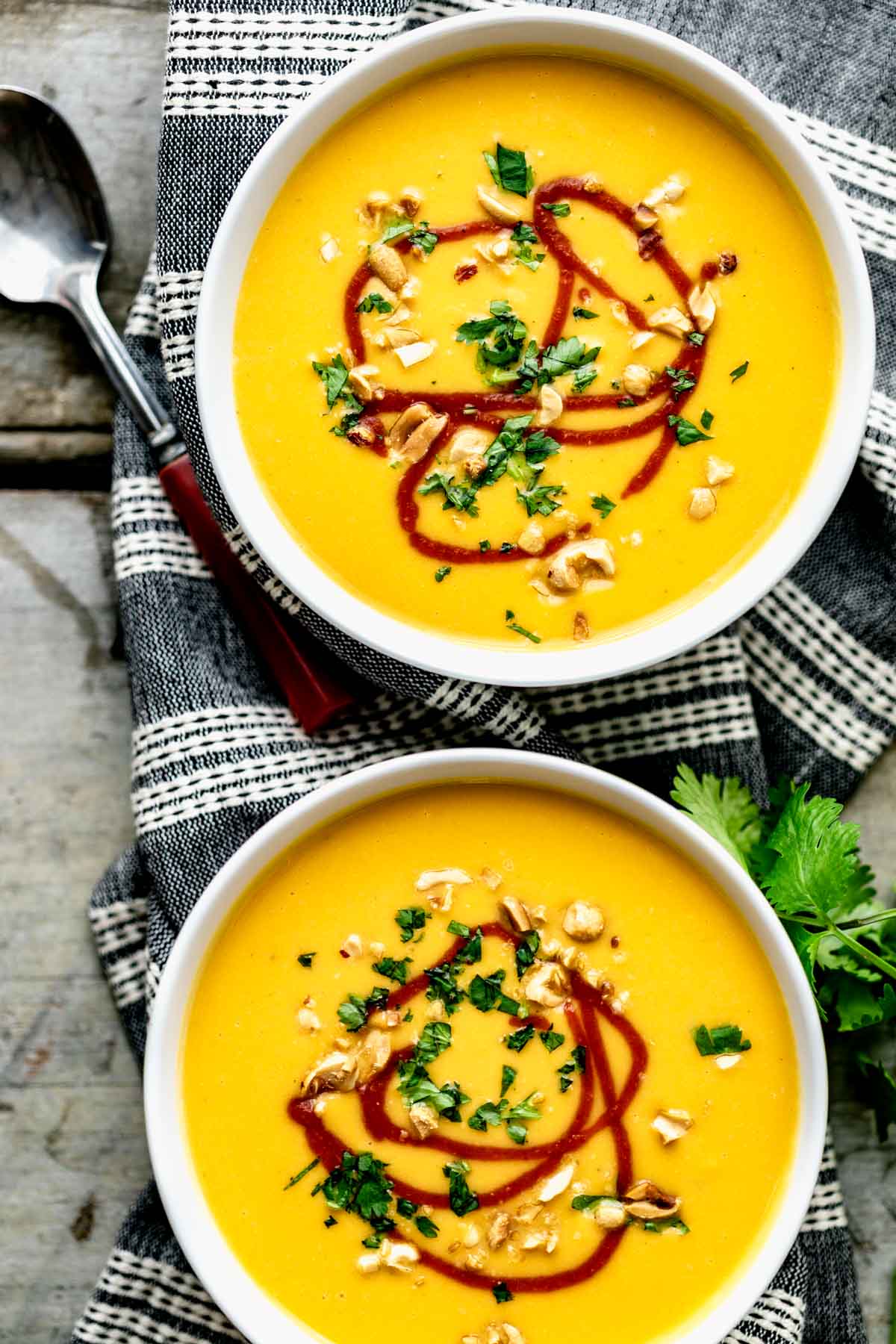 two bowls of soup with sriracha drizzled over the top