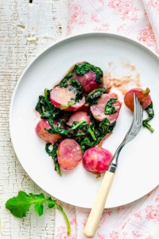 the cooked radishes in miso butter with greens on a plate with a fork