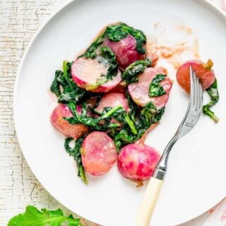 radishes cooked with miso butter on a white plate with greens