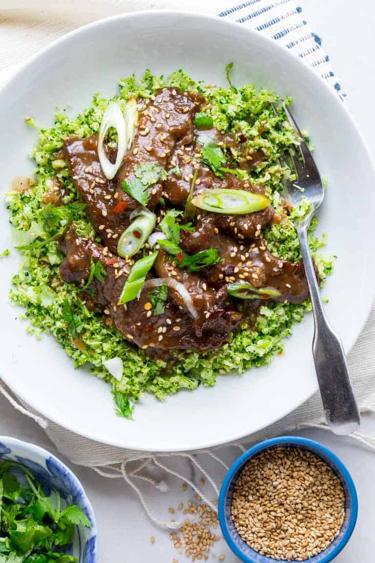 grain free mongolian beef and broccoli bowl topped with a tamari sauce and sesame seeds