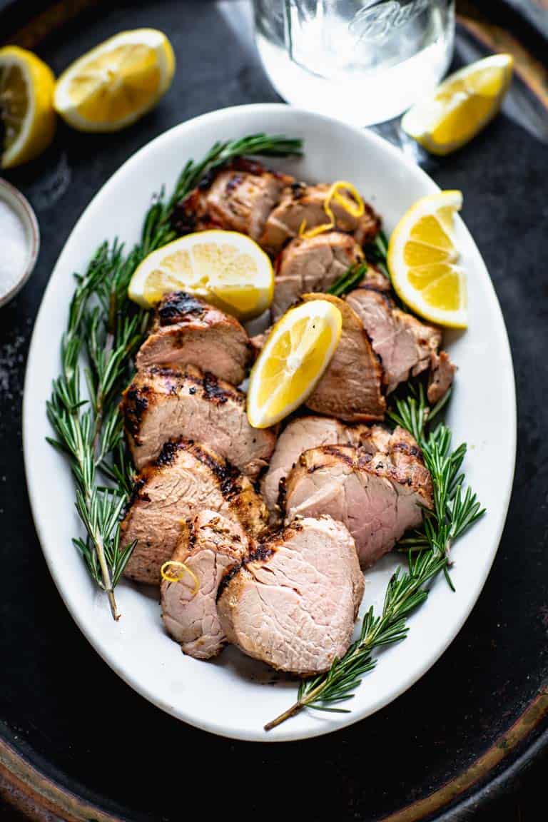 A black try with a platter of pork on it