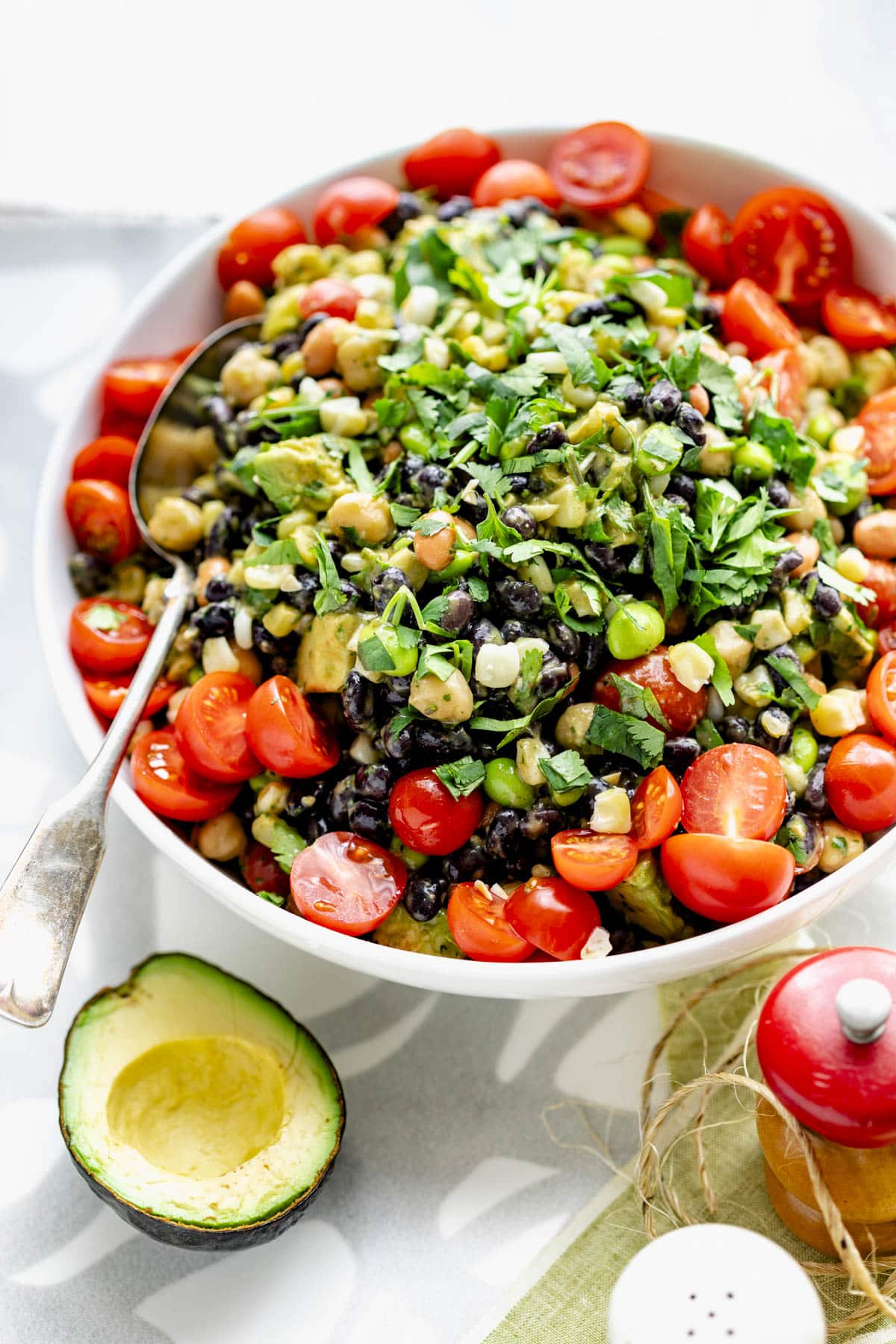 Mexican bean salad in a white bowl with cherry tomatoes arranged decoratively around the rim