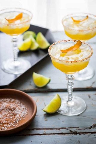 These smoky, tart and sweet Mescal Margaritas, made with Cuantro, freshly squeezed lime and orange juice have a salted rim with a surprising ingredient! #mescal #margarita #cocktail #cincodemayo #vegan #lime #mexican