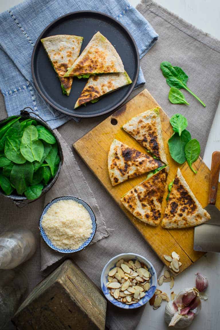 Pesto quesadillas on a cutting board and a plate.