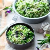 two bowls of blueberry quinoa tabbouleh on a peach and white cloth with edible flowers