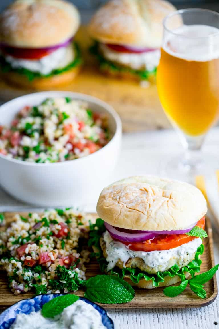 A chicken burger on a plate with a salad alongside