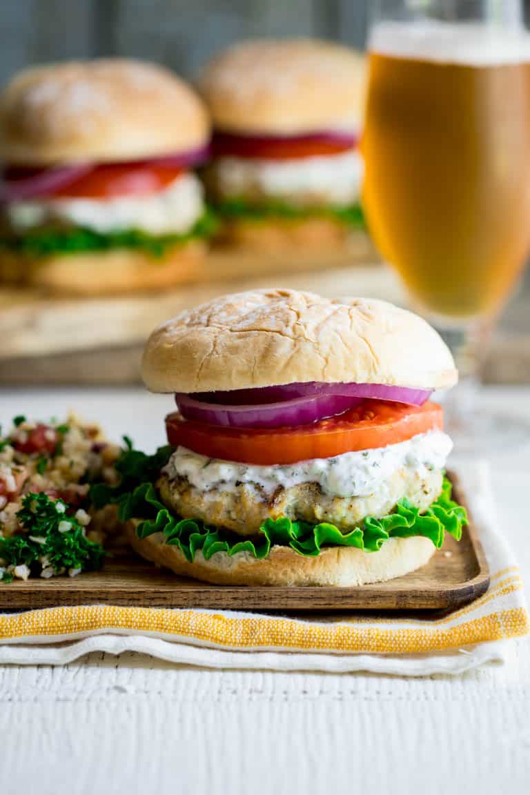 Burgers made from ground chicken, seasoned with za’atar and topped with cucumber mint tzatziki, lettuce and tomato! Get those grills fired up my friends! They’re a middle-eastern flavored burger mash-up you won’t want to miss. Healthy Seasonal Recipes by Katie Webster | #burger #tzatziki #chicken #cucumber #mint #zaatar #grill