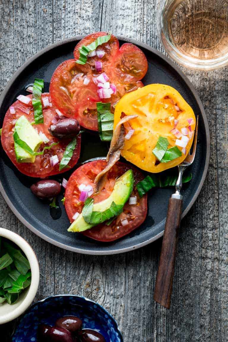 a black plate with tomato salad on it
