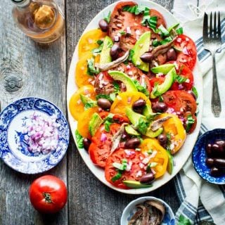 a gray farm table with a platter of tomato salad on it from overhead