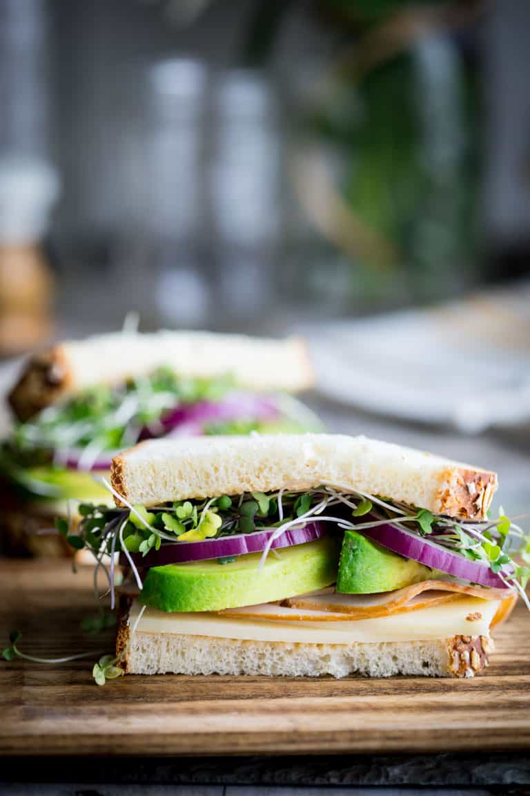 side view of turkey avocado sandwich on a wooden cutting board