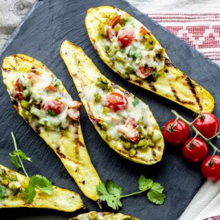 A BLACK SLATE BOARD WITH GRILLED STUFFED SQUASH ON IT
