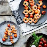 shrimp kabob on a black plate on a gray table