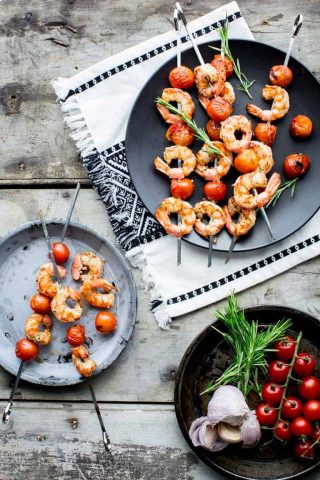 shrimp kabob on a black plate on a gray table