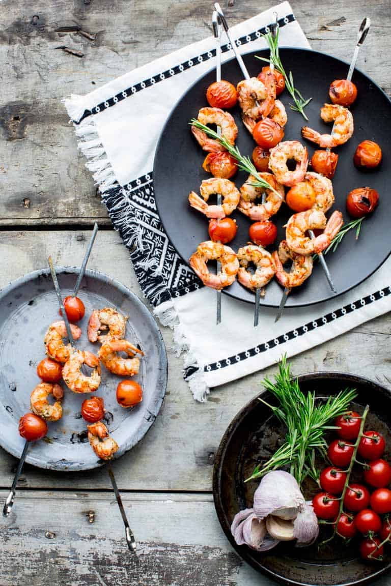 shrimp kabob on a black plate on a gray table