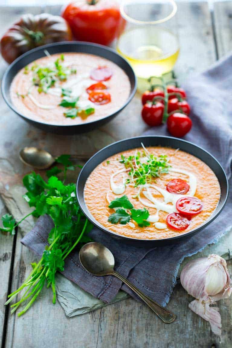 two bowls of gazpacho with tomatoes and herbs
