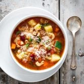 minestrone soup in a white bowl on a gray background