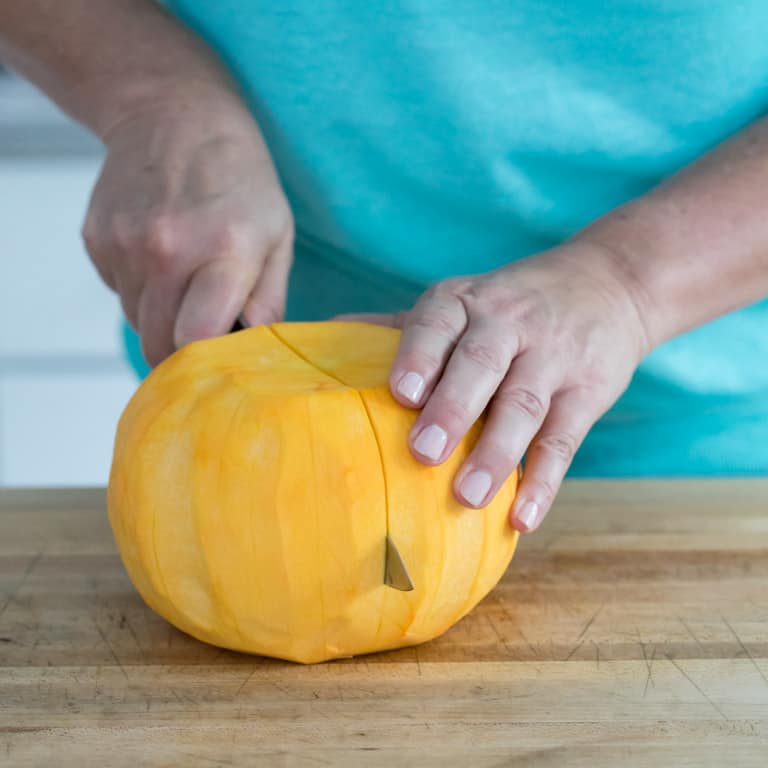 Cut the fresh pumpkin in half after it is peeled.