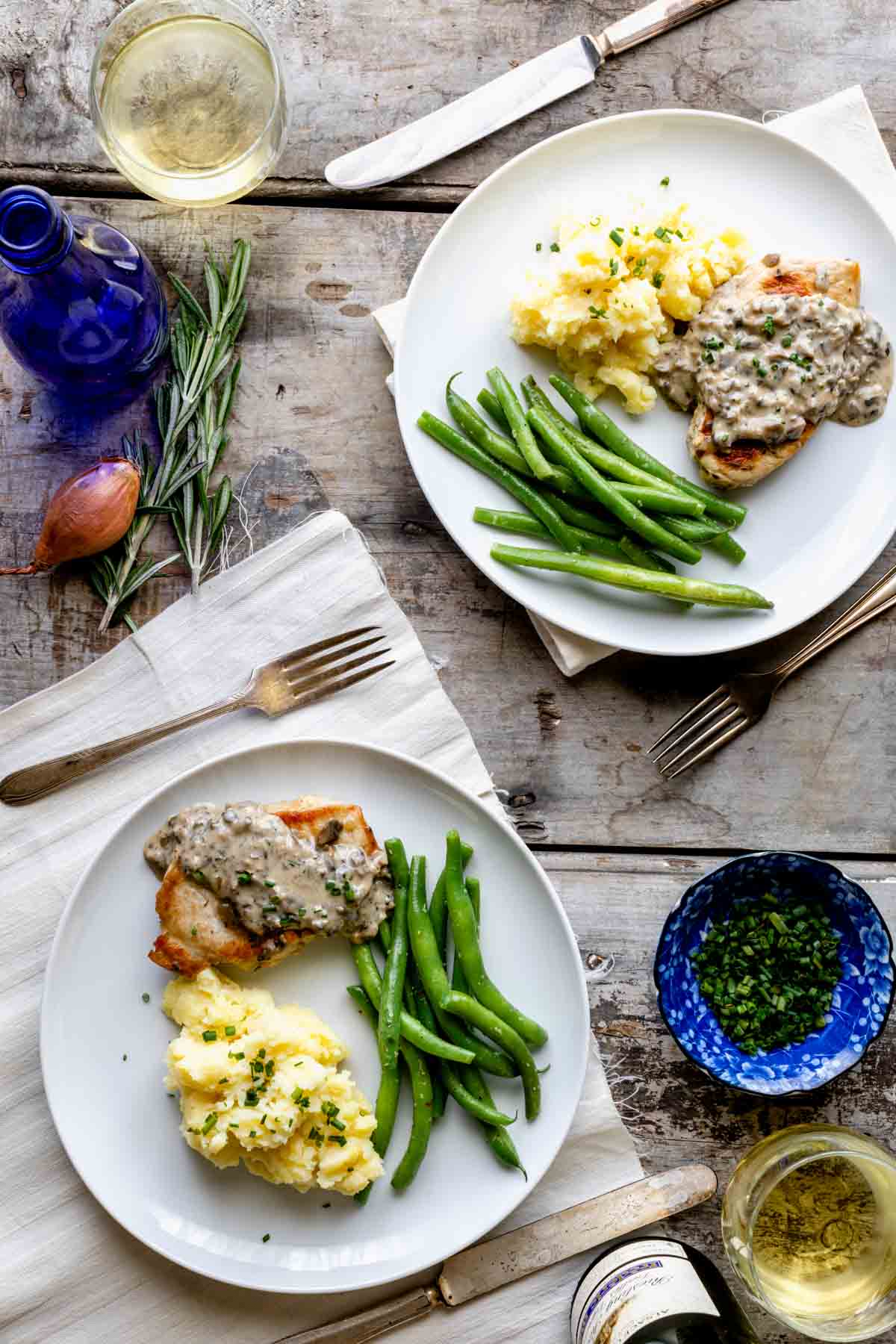 two plates of pork chops, potatoes and green beans