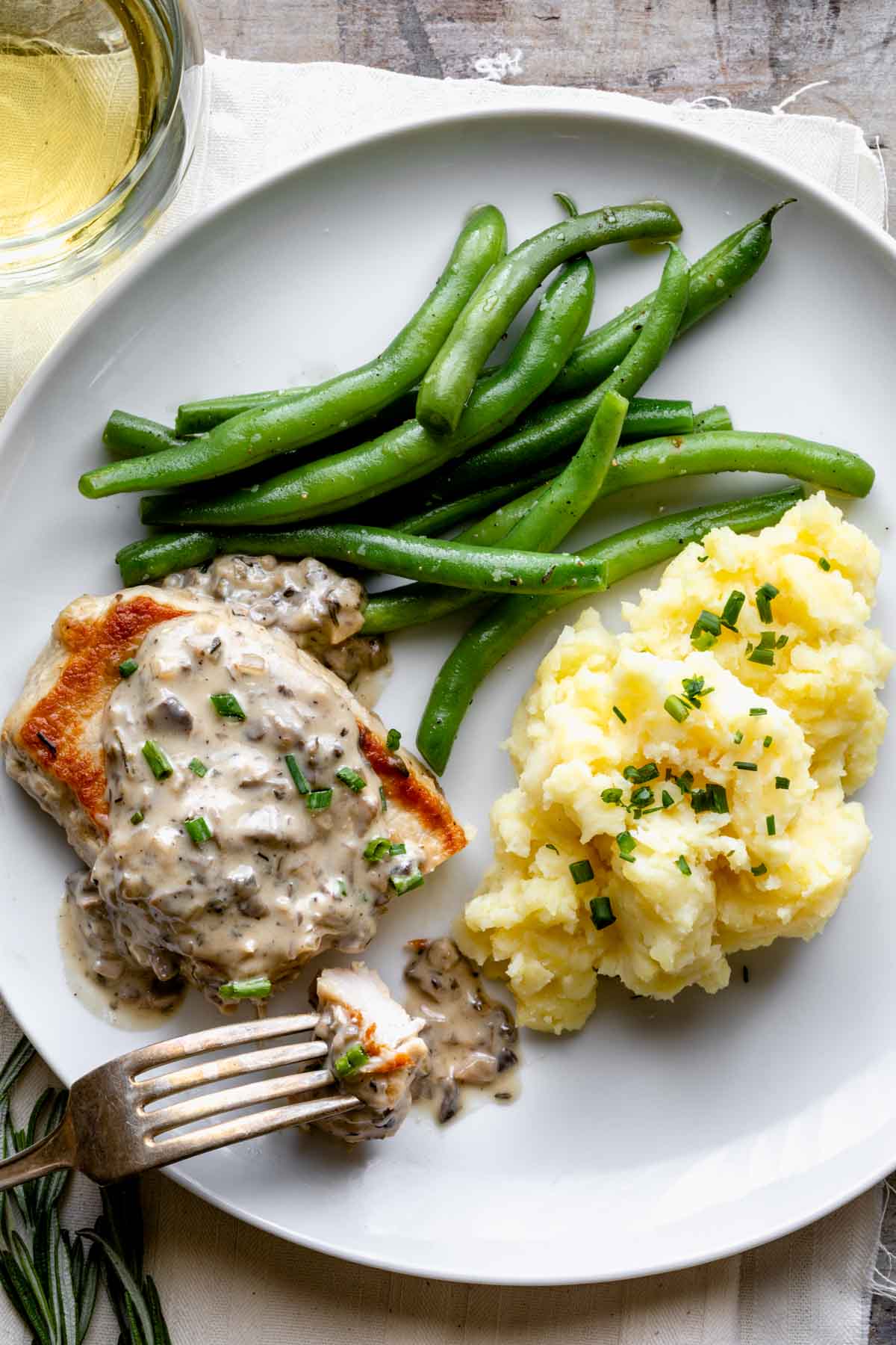 a pork chop on a plate with mashed potatoes and green beans