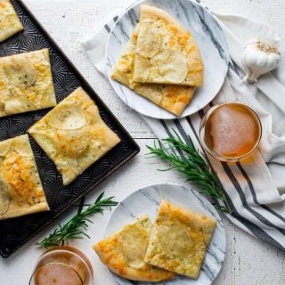 Have you heard of potato pizza before? If not, keep an open mind, and prepare your taste buds for a surprisingly delicious combination. In this white pizza version, I have a bit of rosemary, garlic and cheddar cheese to make it super savory and yummy! #vegetarian #pizza #whitepizza #potato #cheddar