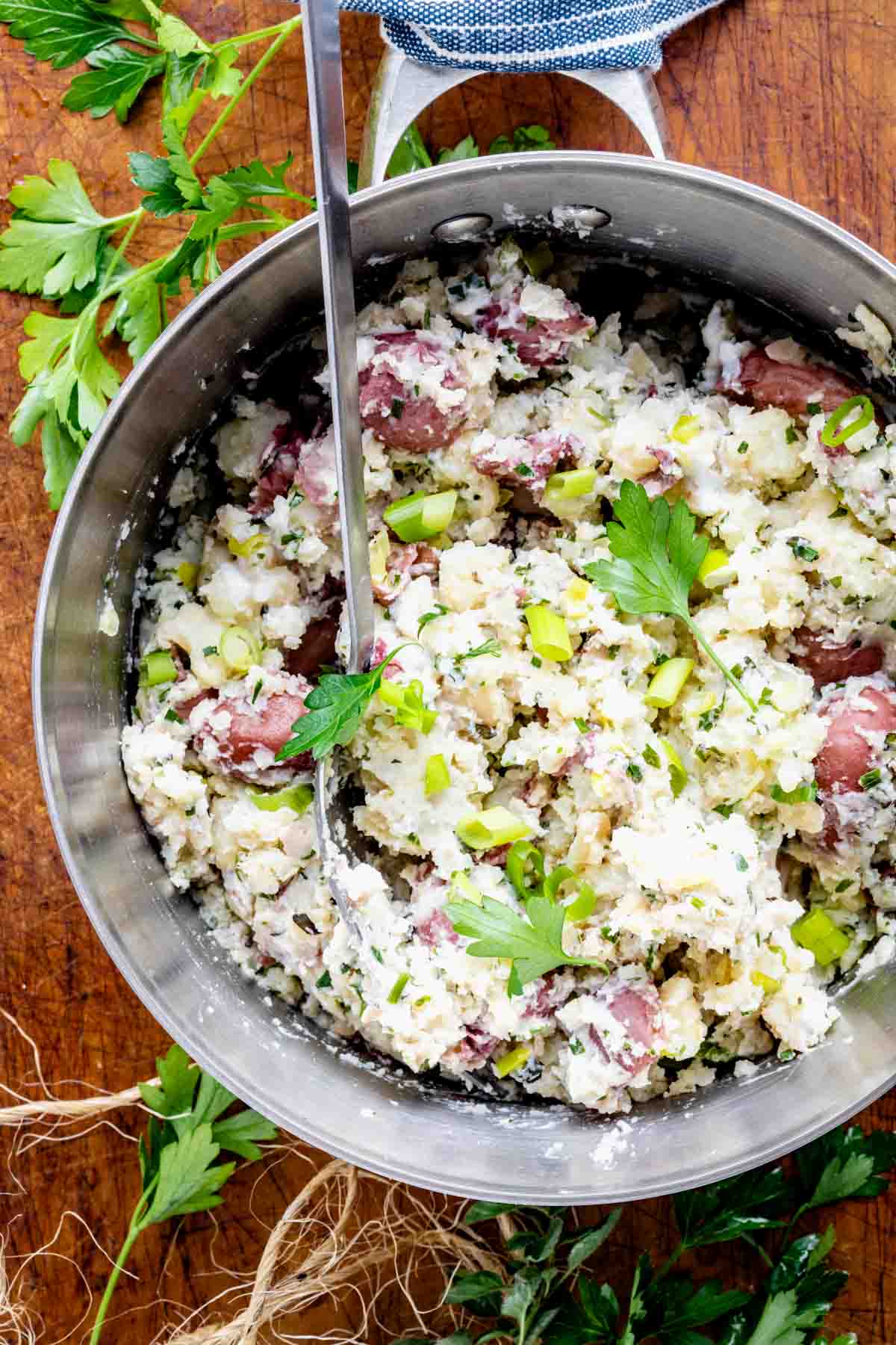 a closeup in the pot of the mashed potatoes with parsley and scallions