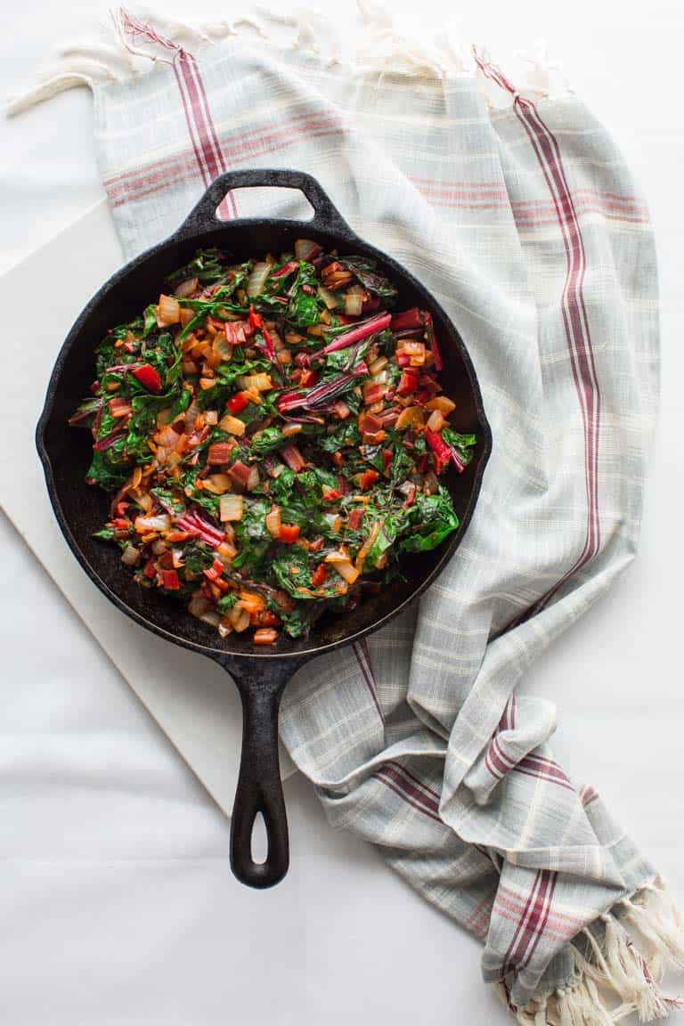 A white table and gray cloth with a skillet with chard in it