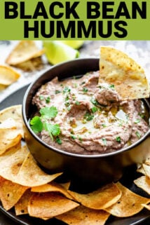 black bowl of hummus with a tortilla chip dunking in