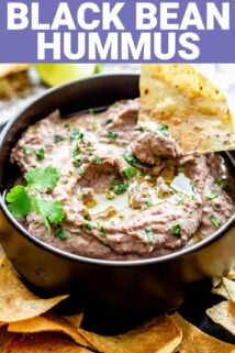 black bowl of hummus with a tortilla chip dunking in