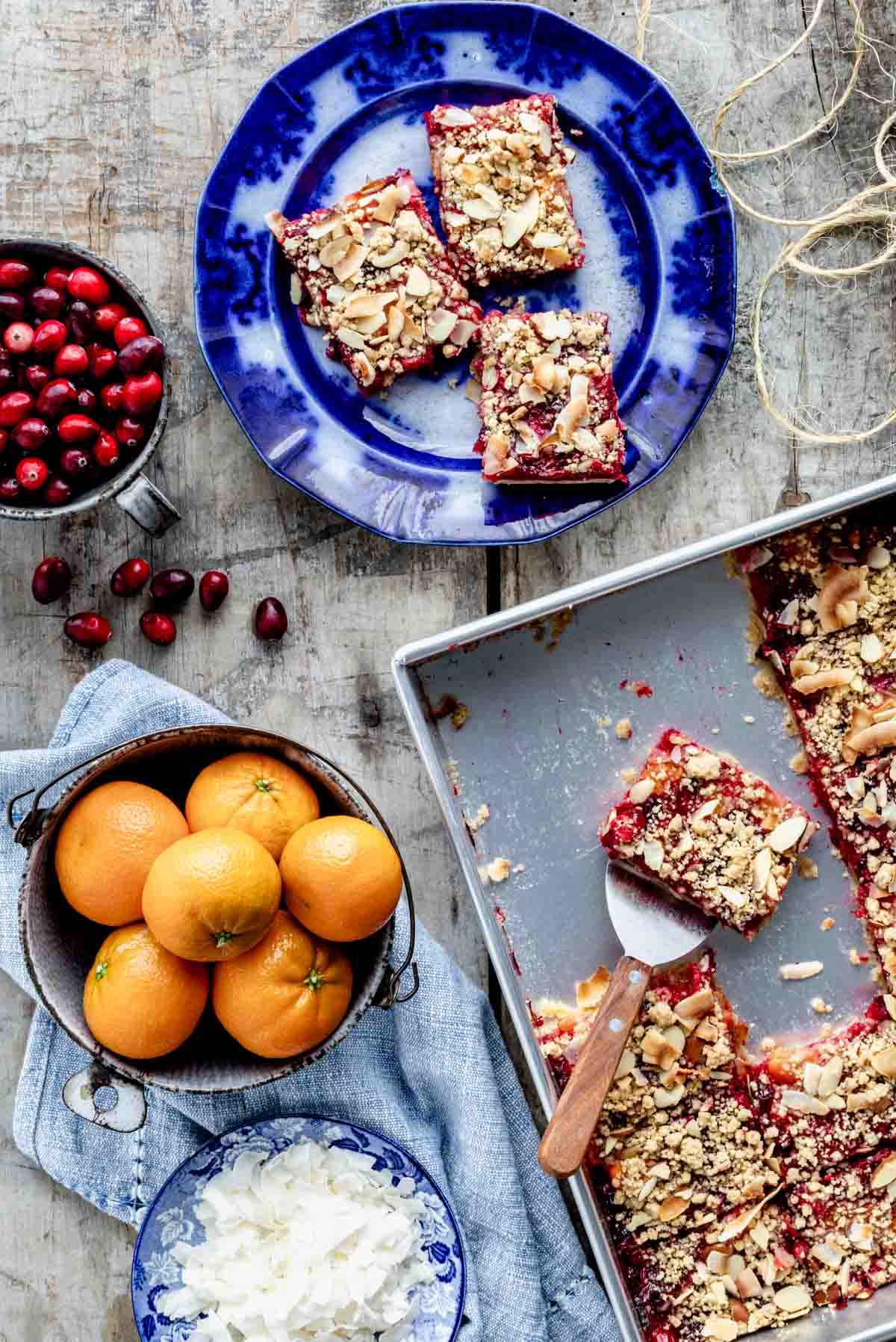 overhead of the pan of bars with a bowl of clementines, coconut and cranberries