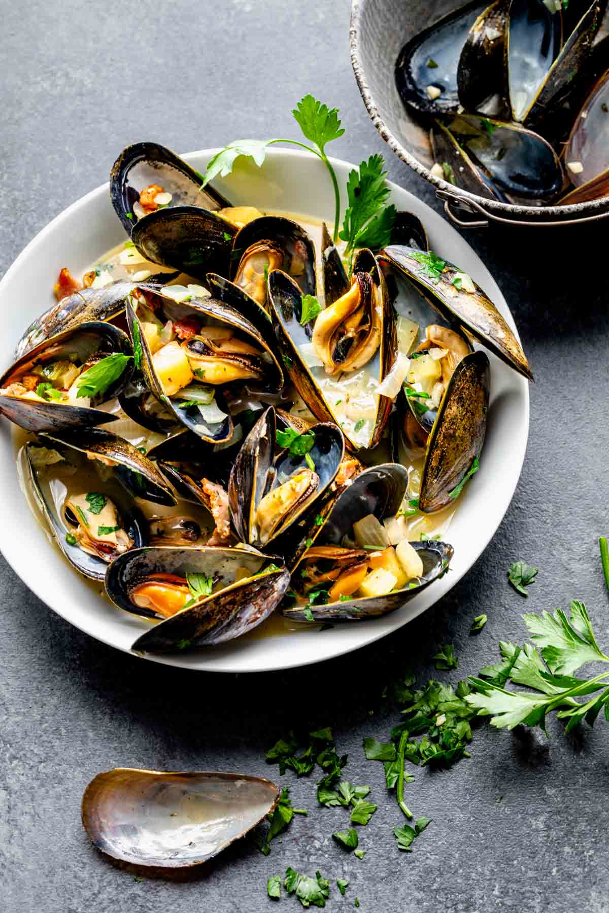 A black table with a white bowl with mussels
