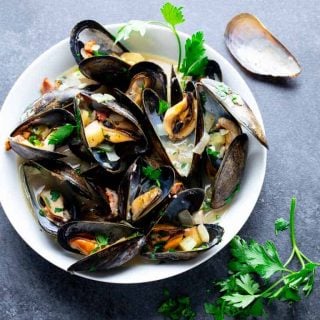 mussles in a white bowl on a gray table