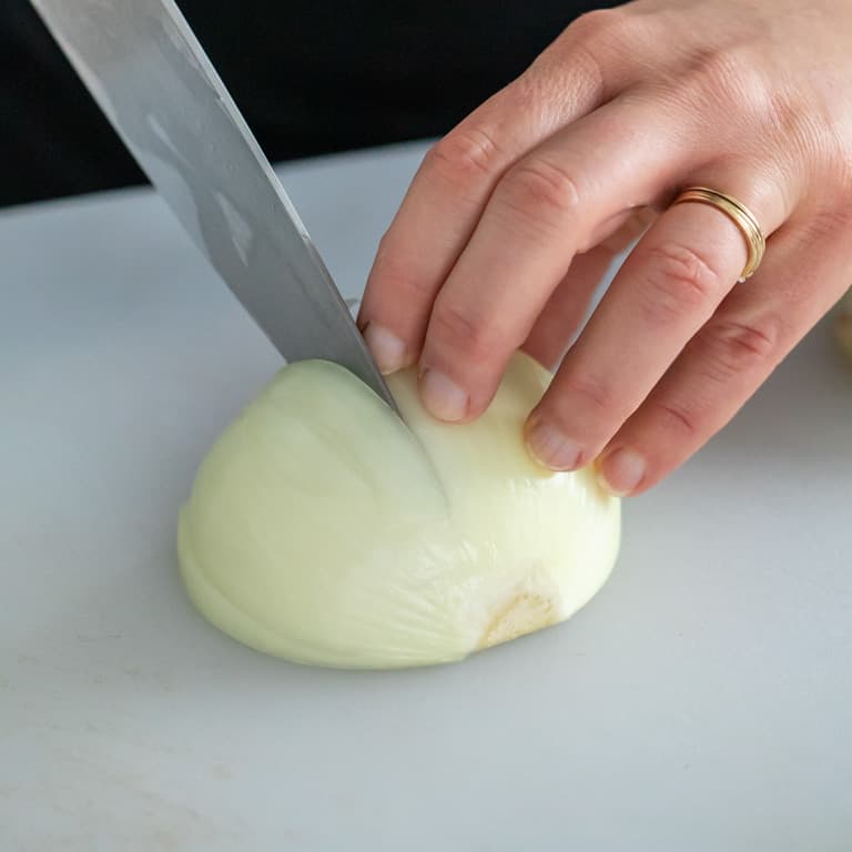 Slice the onion, with knife tip stopping just short of the root end into equally thick slices.