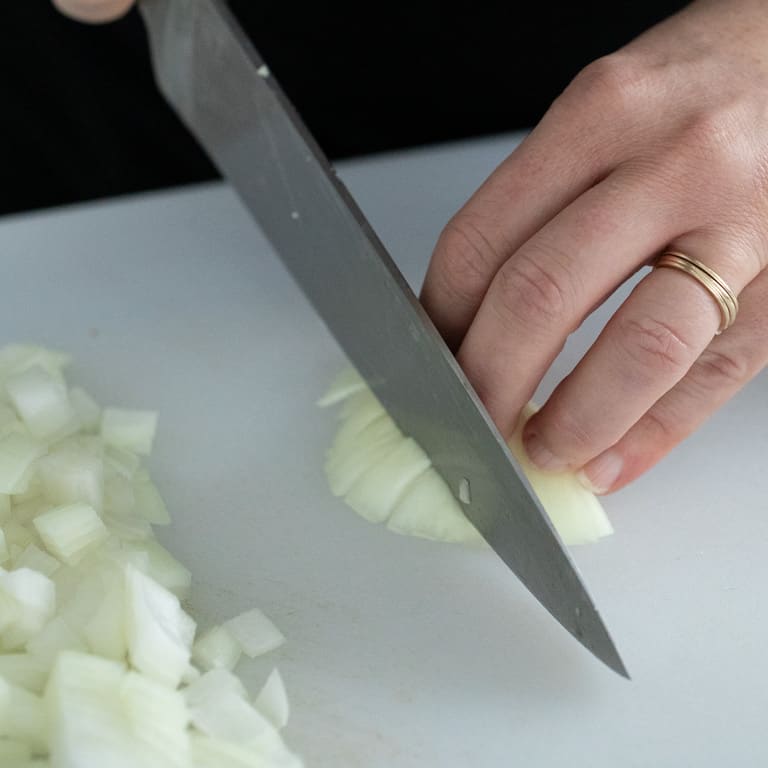 Cut around the root end to use all edible parts of the the onion and limit waste.