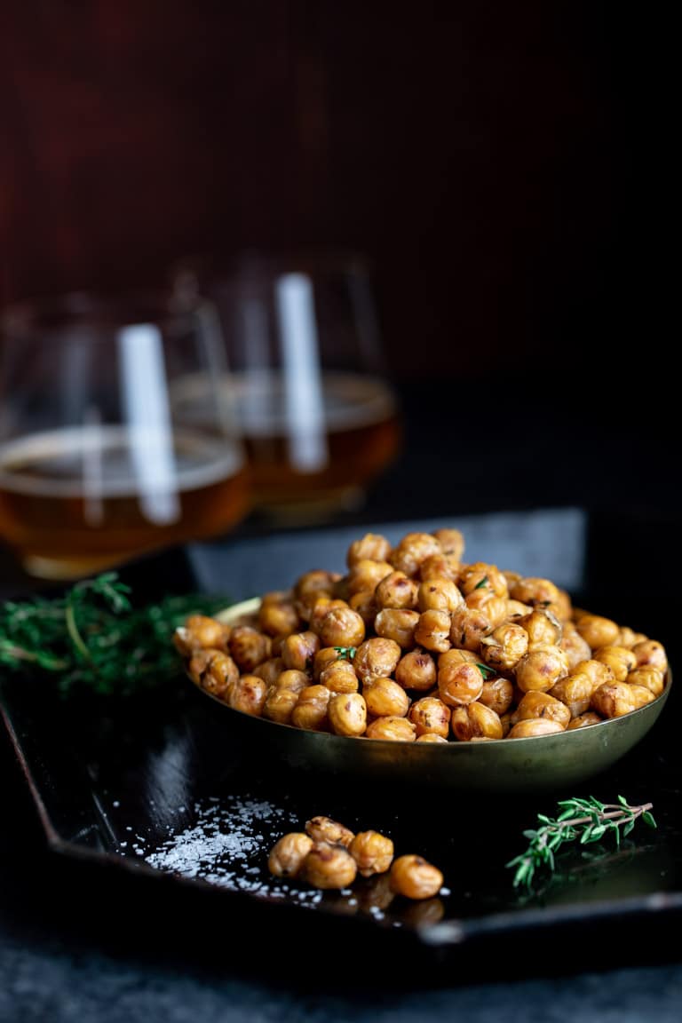 bowl of crispy roasted chickpeas with 2 glasses of beer and fresh thyme