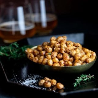 bowl of crispy roasted chickpeas with 2 glasses of beer and fresh thyme