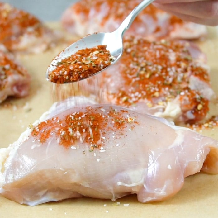 sprinkling spices over the Chicken