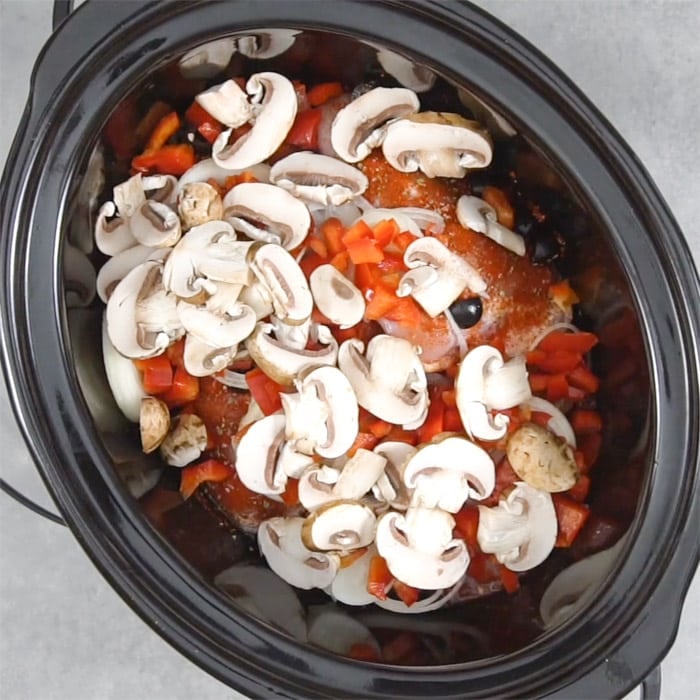 the mushrooms on top of the food in the slow cooker
