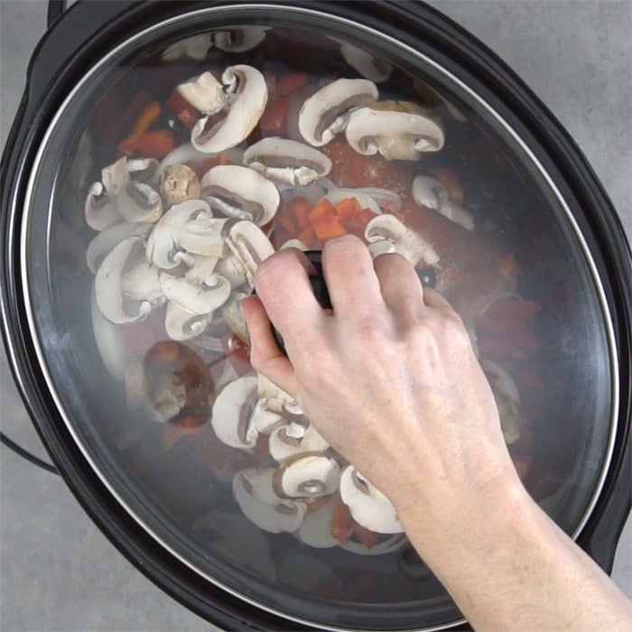 a person putting the lid on top of the slow cooker