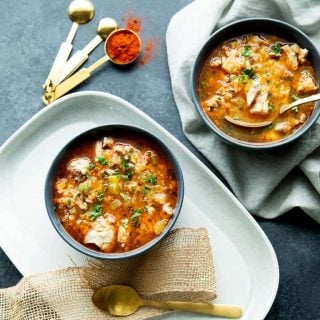 Two bowls of keto chicken soup with two spoons and measuring spoons with paprika