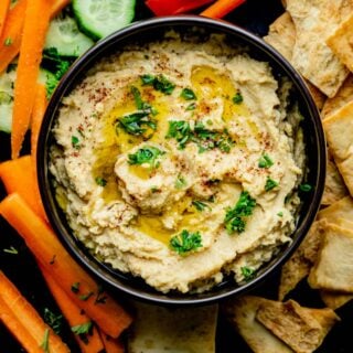 close up of the hummus in a black bowl with parsley on top