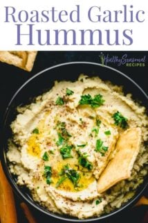 Close up of a bowl of hummus with a pita chip in it
