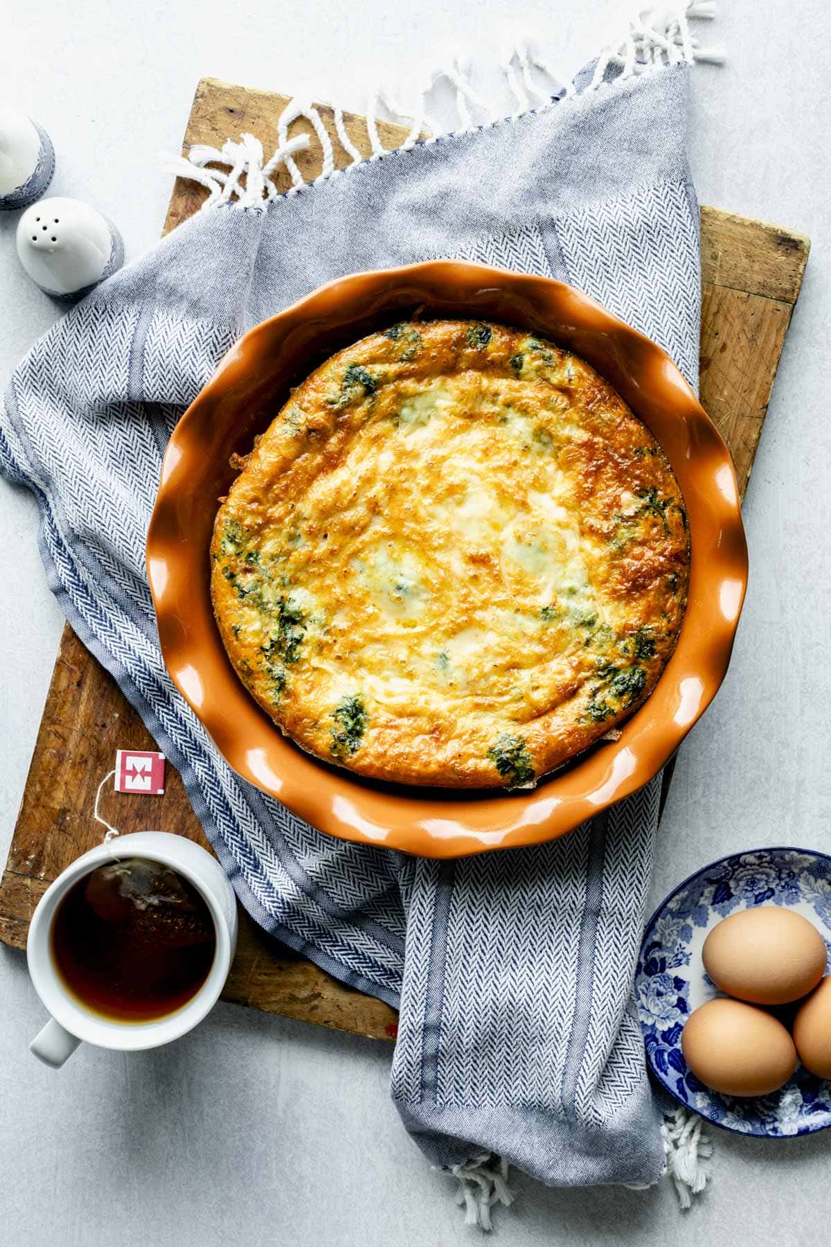 the egg bake in the pie plate from overhead on a blue dish cloth
