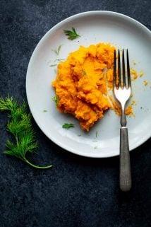 A white plate with mashed parsnips and carrots on it.
