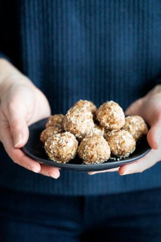 hands holding a plate of paleo energy balls