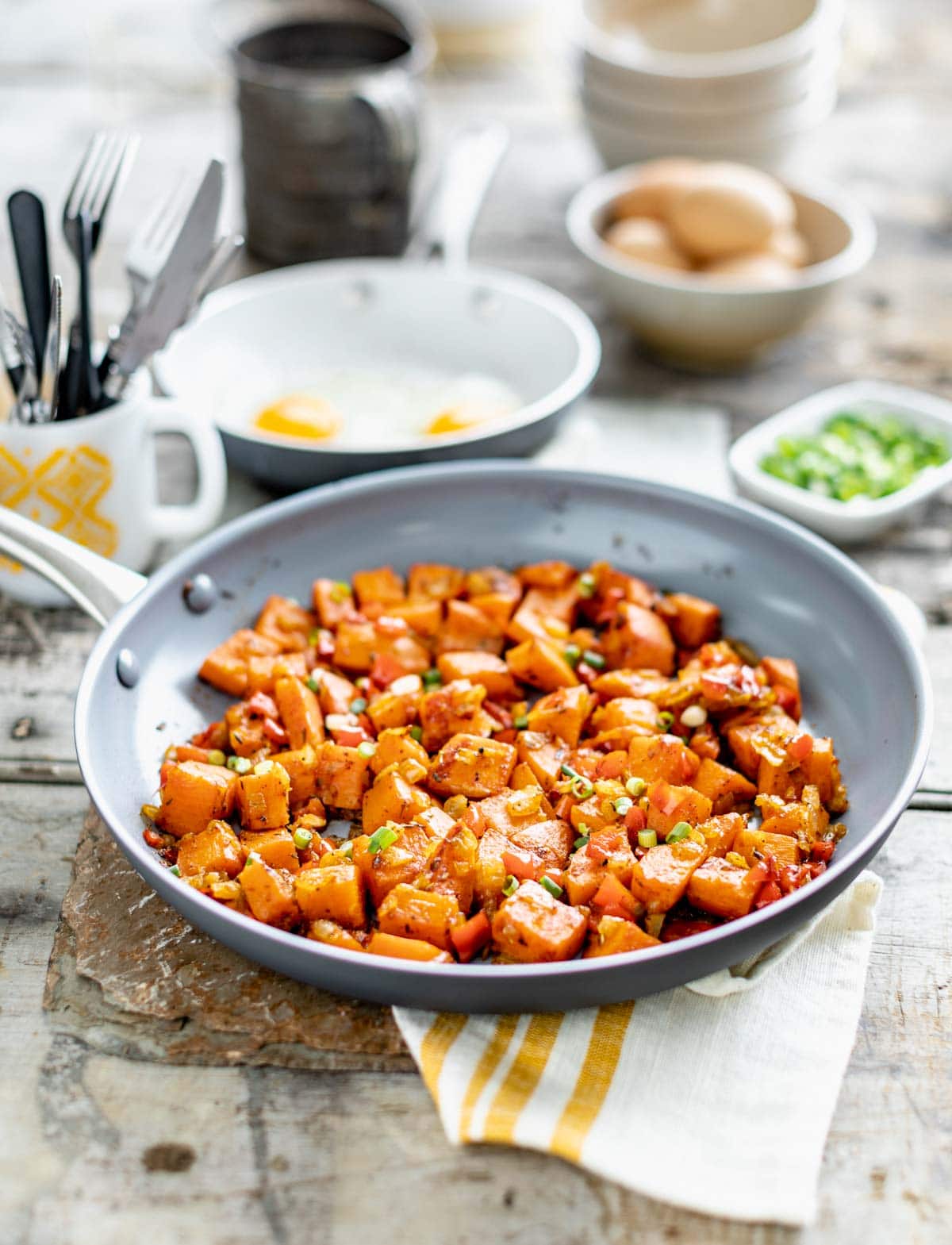side view of hash in a skillet with a brunch meal set out on the table